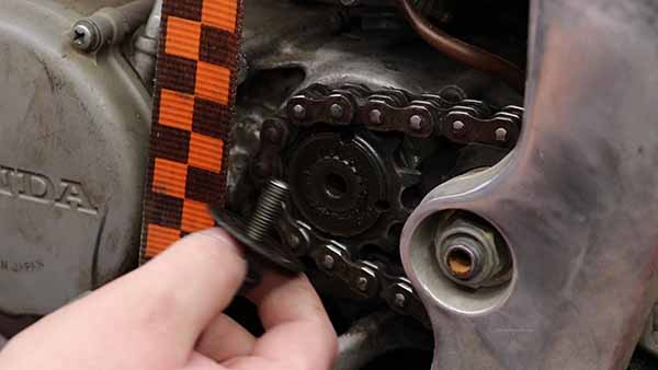 With the rear brake engaged, loosen and remove the front sprocket bolt, washer, and sprocket from the countershaft.