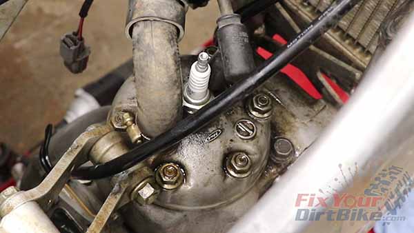 Remove the coolant hose and spark plug from the cylinder head.